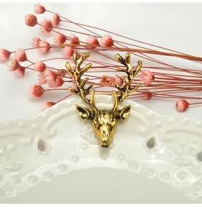 Close-up of vintage gold deer head brooch resting on a decorative white ceramic dish.