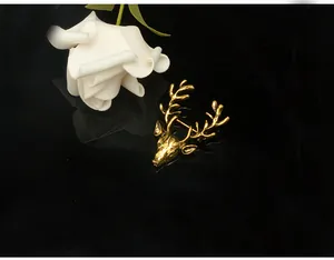 Close-up detail shot of a vintage gold deer head brooch with intricate antlers resting on black.