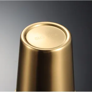 Stainless steel pint cup bottom detail, titanium gold brushed metal finish texture close-up.