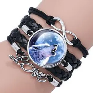 Detail of multi-layer braided leather bracelet featuring wolf glass cabochon and charm.