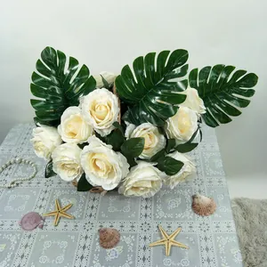 Bouquet de roses artificielles blanches avec feuilles de monstera dans un panier déco