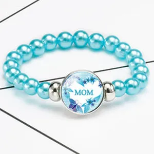 Detail of light blue glossy pearl bracelet with MOM heart pendant for Mother's Day