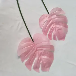 Vue détaillée de feuilles de monstera artificielles roses avec tiges vertes pour déco maison.