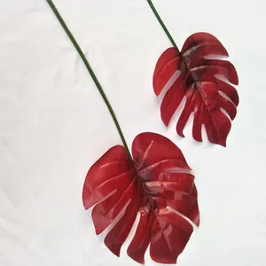 Vue détaillée de feuilles de monstera artificielles rouges avec de longues tiges vertes.