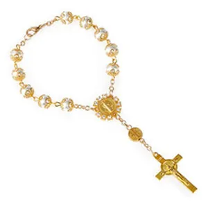Vista detallada de pulsera de rosario religioso en oro con cuentas blancas y crucifijo