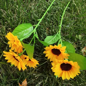 Détail de tournesol artificiel, tête de fleur en soie jaune vif avec feuilles sur herbe.