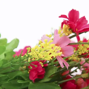 Primo piano dettagli di fiori di margherita artificiali, petali vivaci e foglie verdi.