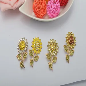 Close-up details of four sparkling rhinestone sunflower brooches with green enamel leaves.