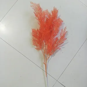 Orange artificial pine branch fern plant for wedding home floral background decor detail view.