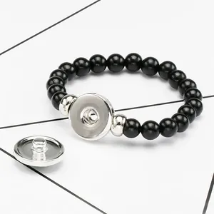 Detailed view of black beaded elastic bracelet featuring a silver snap button mechanism