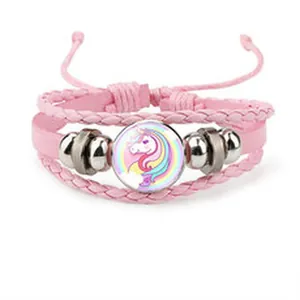 Detail of pink braided bracelet featuring a colorful cartoon unicorn glass cabochon center