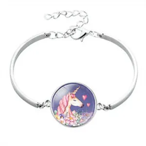 Close-up detail showing a silver unicorn bracelet with a pink heart and flower pendant
