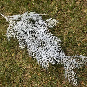 Detalle de rama de pino artificial escarchada para decoración de bodas y hogar.