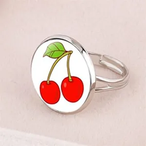 Detailed view of an adjustable silver ring featuring a vibrant cartoon cherry design on a white base