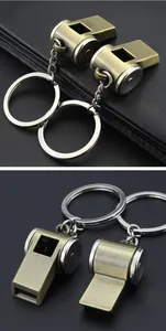 Close-up details of vintage metal whistle keychain, bronze finish with silver split rings.
