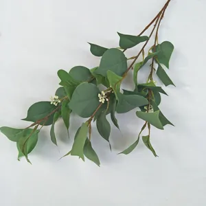 Artificial green plant branch detail shot, realistic leaf texture and small white berries decoration.