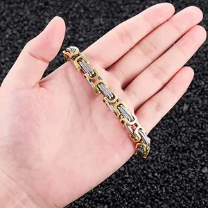 Close-up view of a two-tone gold and silver Byzantine chain bracelet held in a person's hand