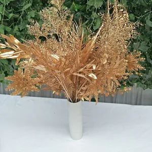 Gold artificial plant bouquet detail, fake maple and fern leaves, wedding floral decor.