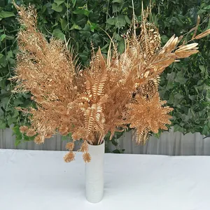 Gold artificial plant bouquet detail shot, elegant gold fern leaves for wedding decor setup.