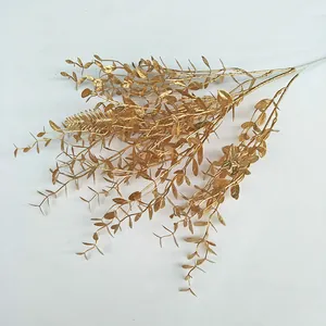 Gold artificial plant branch detail, wedding decorative floral arrangement, shimmering gold eucalyptus leaves.
