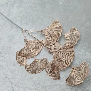 Close up of gold artificial ginkgo leaf branch, metallic texture for wedding home decor.