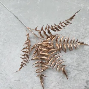 Gold artificial fern leaf branch fake plant for wedding home decor floral arrangement detail view.