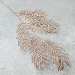 Close-up detail of golden artificial feather fern branch for wedding and home decoration.