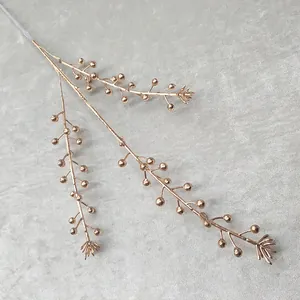Detailed shot of gold artificial plant branch with small decorative berries for display.