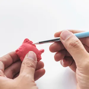 Silicone clay sculpting pen detail shot showing soft white tip shaping pink pottery model.