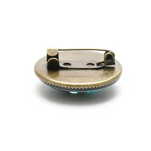 Back view of an antique bronze brooch pin with a teal glass cabochon base.