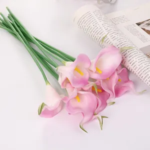 Gros plan détaillé de fleurs de lys calla artificielles avec des têtes roses et des tiges.