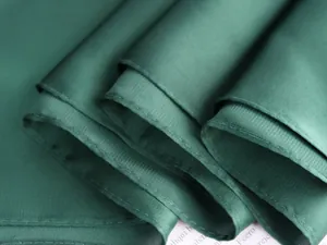 Dettaglio macro della trama del tessuto in raso verde scuro e cuciture dei bordi curati