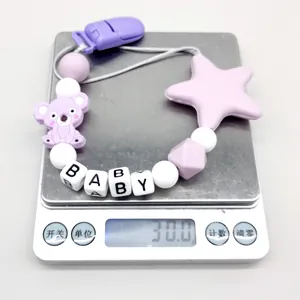 Silicone koala and star baby pacifier clip weighing 30.0 grams on a digital scale