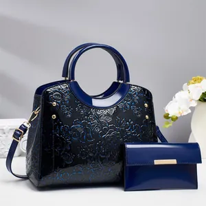 Elegant navy blue handbag and wallet set with embossed floral patterns and glossy finish