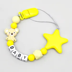 Detail showing silicone koala and star charms on a yellow baby pacifier clip