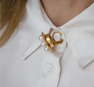 Close-up detail of a vintage metal pearl decorative button attached on a white shirt collar.