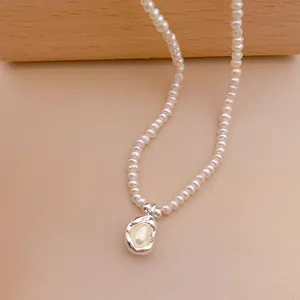 Detailaufnahme einer minimalistischen Süßwasserperlenkette mit unregelmäßigem Anhänger.