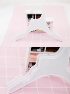 Detail shot of white plastic small clothes hangers for pet or kids clothes, hook and slot design.