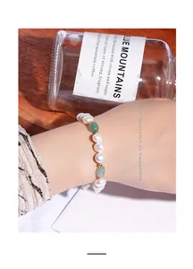 Macro view of irregular freshwater pearl and green aventurine stone bracelet on wrist.