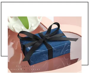 Detailed view of dark blue gift box wrapped with elegant black grosgrain ribbon bow for packaging.