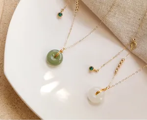 Nahaufnahme von grünen und weißen Hetian-Jade-Anhängern an zarten Goldketten