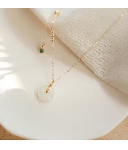 Detaillierte Makroaufnahme eines weißen Hetian-Jade-Anhängers an einer feinen Goldkette