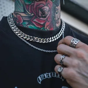 Close-up detail of silver titanium steel thick Cuban link and rope chain necklaces on man