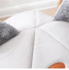 Primer plano detallado de cama gris de felpa para mascotas con orejas y parche de cuero.