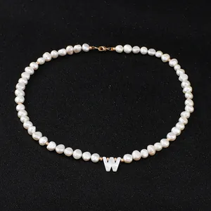 Detailed shot of freshwater pearl necklace featuring mother-of-pearl letter W pendant.
