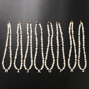 Freshwater pearl necklace detail featuring natural shell letter pendants displayed neatly.