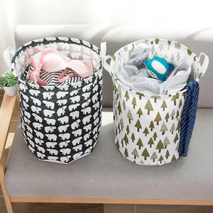 Two stylish foldable fabric laundry hampers with bear and pine tree patterns on sofa