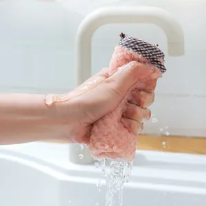 Absorbent pink coral fleece hand towel being squeezed in a clean kitchen sink