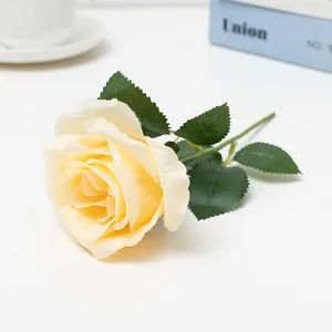 Detailed view of an artificial yellow rose flower with green leaves for home and wedding decor.