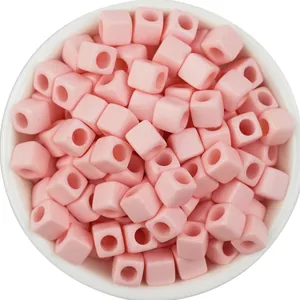 Close-up detail of light pink acrylic square beads with large holes for DIY jewelry crafting.